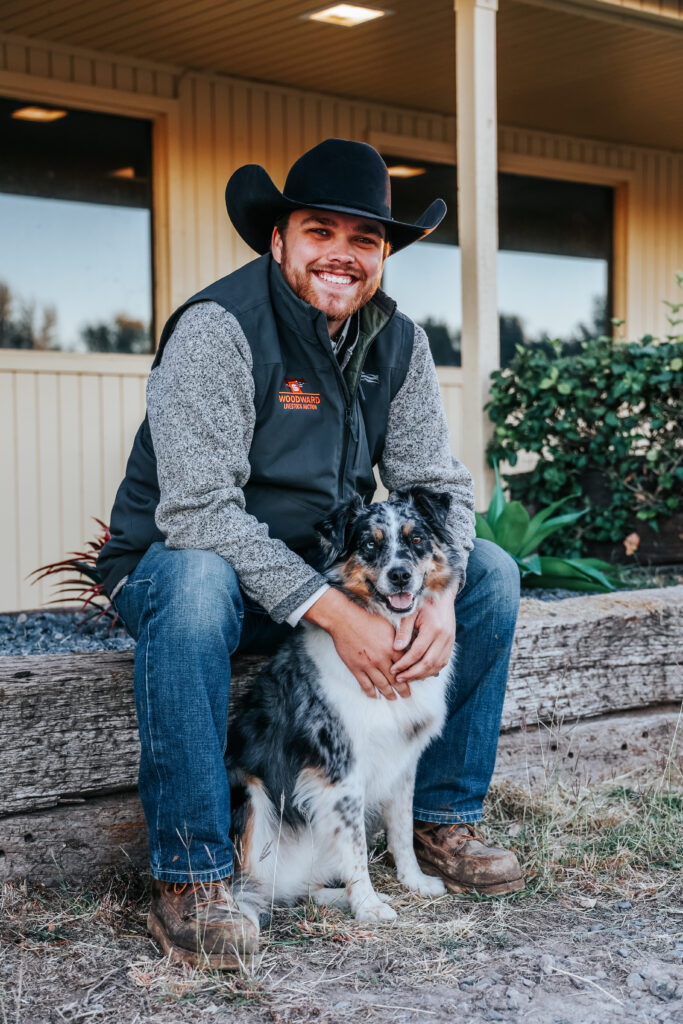 Seth Hale, manager of Woodward Livestock Auction, and his dog Beau standing in front of the sale barn entrance.